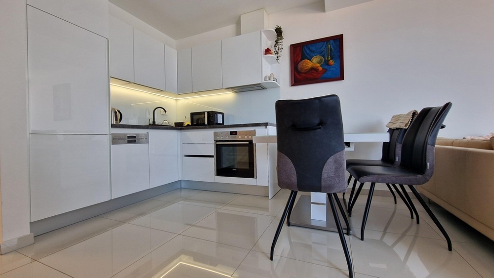 Przestronna, otwarta kuchnia z jadalnią i nowoczesnym wyposażeniem, w tym sprzętem do zabudowy.