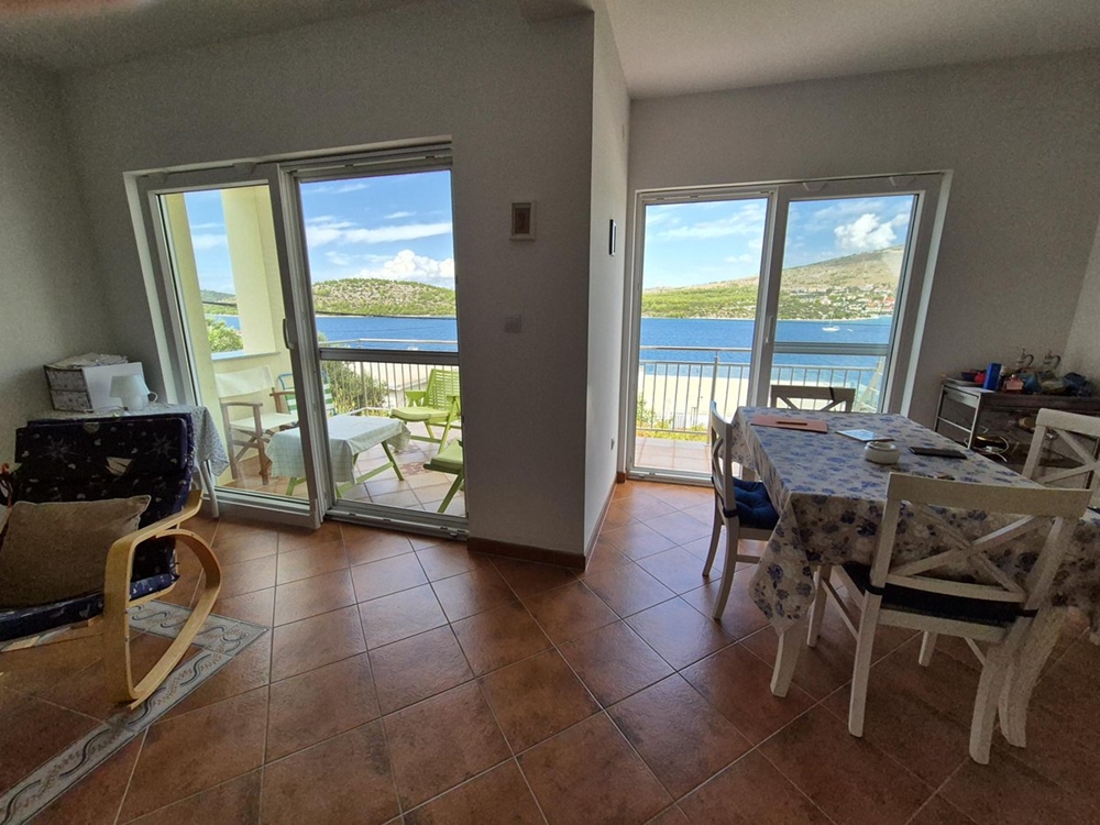 Salon z dużą przesuwaną witryną przeszkloną wychodzącą na taras z widokiem na morze.