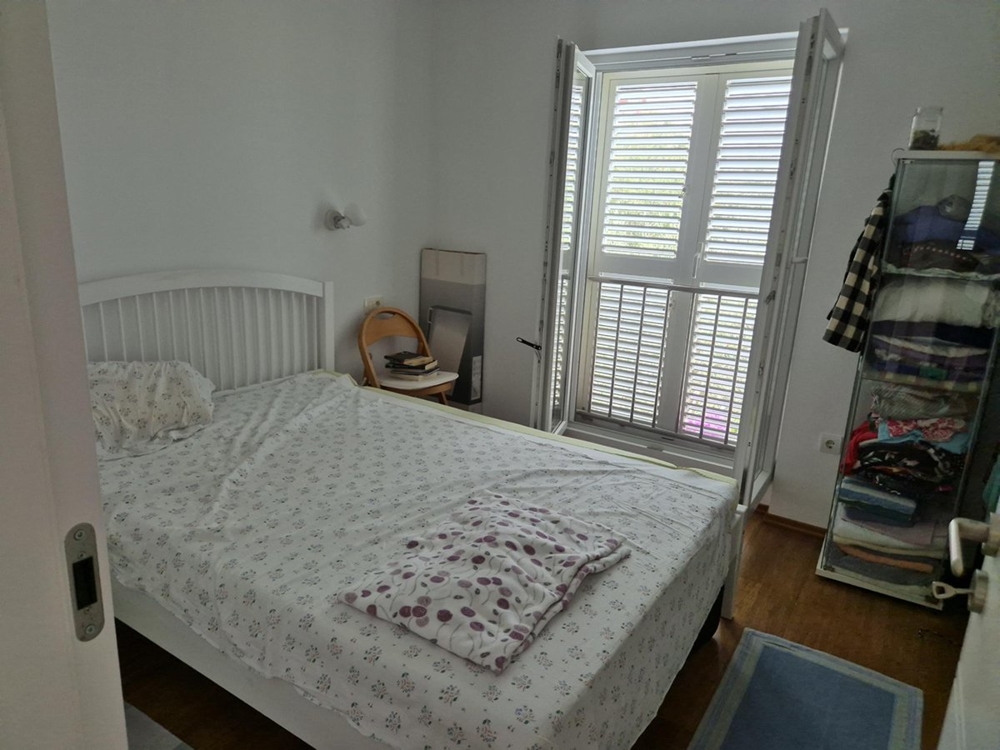 Sypialnia z podwójnym łóżkiem, białymi meblami i oknem