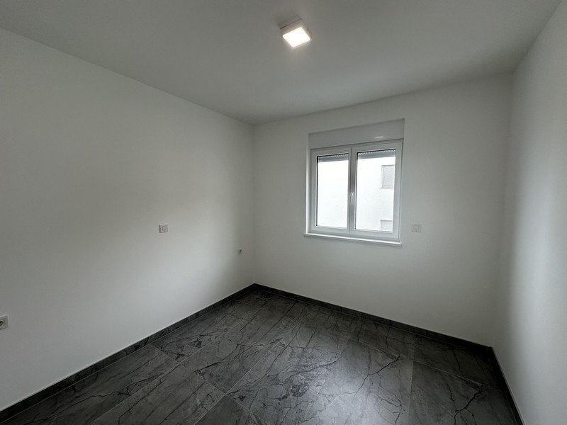 Pusta sypialnia z podłogą wyłożoną kafelkami i oknem