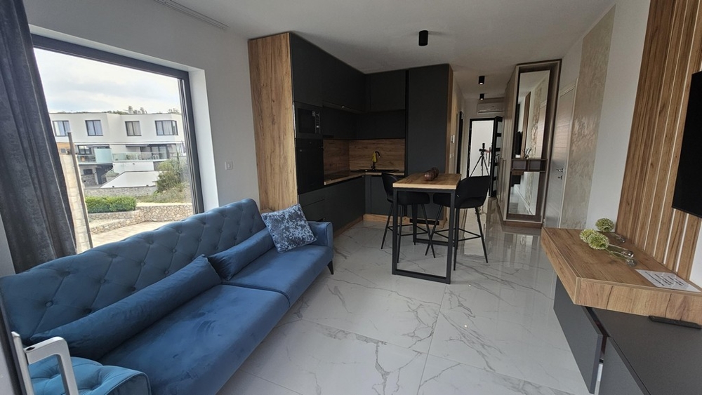 Część dzienna z sofą, przylegająca kuchnia i balkon