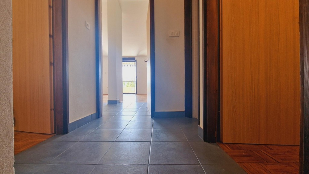 Przedpokój wyłożony płytkami, drzwi do sypialni i salonu.