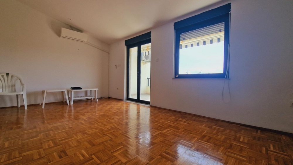 Jasny salon z parkietem, wyjściem na taras, dużymi oknami.