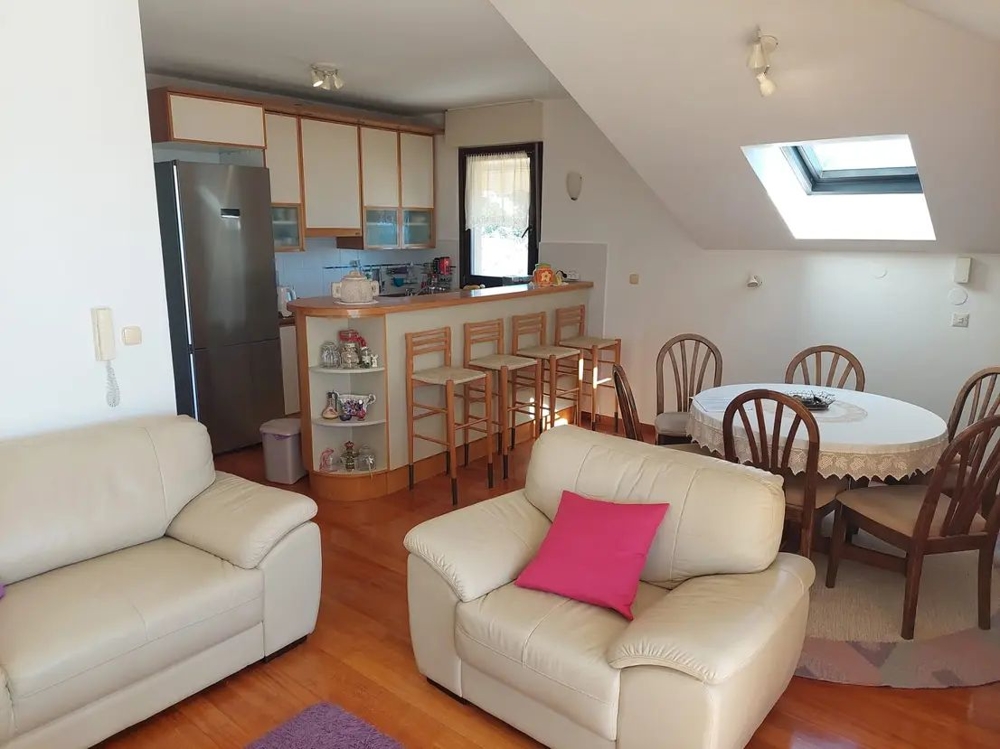 Przytulny salon z kuchnią, barem i stołem jadalnym w mieszkaniu na poddaszu