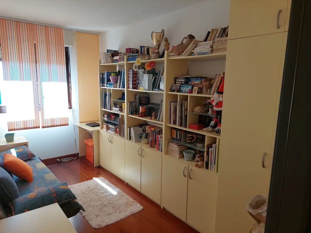 Pokój z półkami na książki, biurkiem i sofą, jasnymi oknami