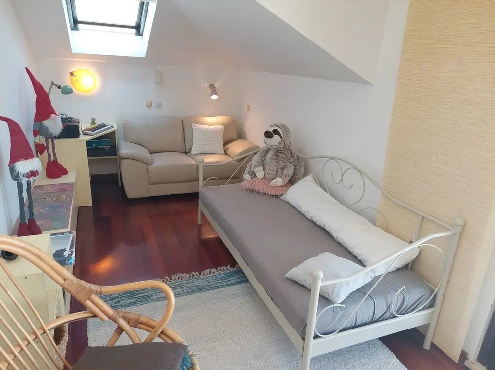 Pokój z łóżkiem, sofą, świetlikiem i dekoracjami, w tym pluszowymi zwierzętami