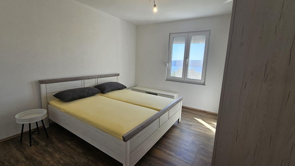 Sypialnia z łóżkiem małżeńskim i oknem z widokiem na morze.