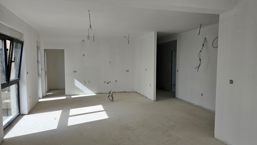 Niewykończony salon z otwartymi oknami i przygotowanymi przyłączami do kuchni