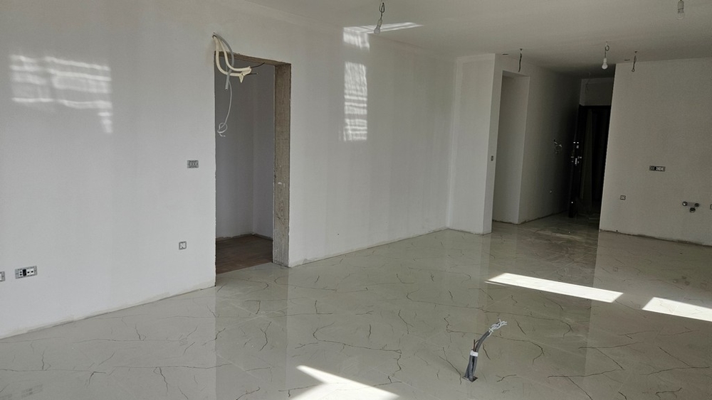 Pokój niedokończony z jasnymi płytkami podłogowymi, gotowy do dalszych prac wykończeniowych