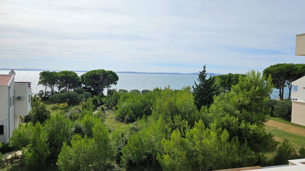 Widok na morze z drugiego piętra otoczony zieloną roślinnością i drzewami