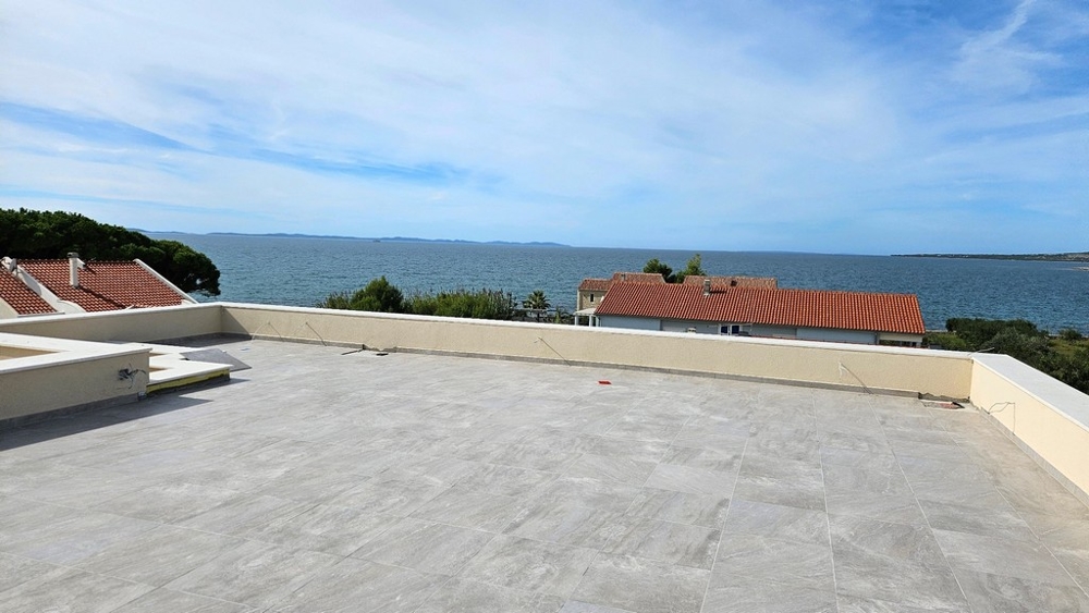 Taras na dachu z panoramicznym widokiem na morze i czerwone dachy domów poniżej