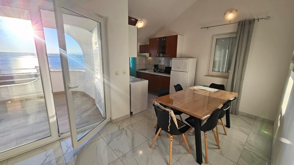 Widok na taras, stół jadalny i aneks kuchenny.