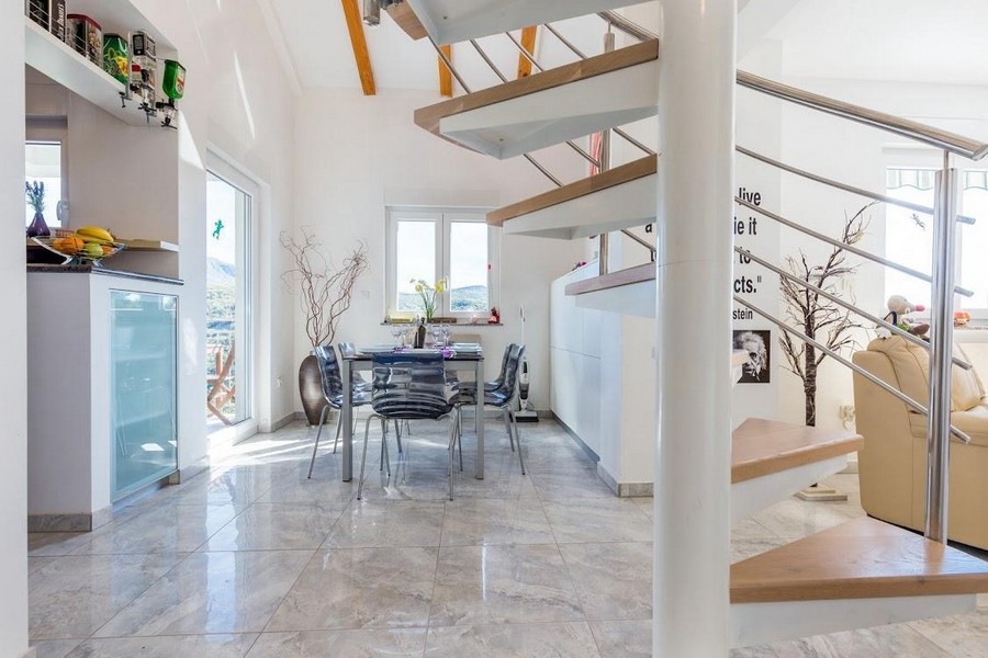 Jadalnia ze szklanym stołem i krzesłami, w tle schody