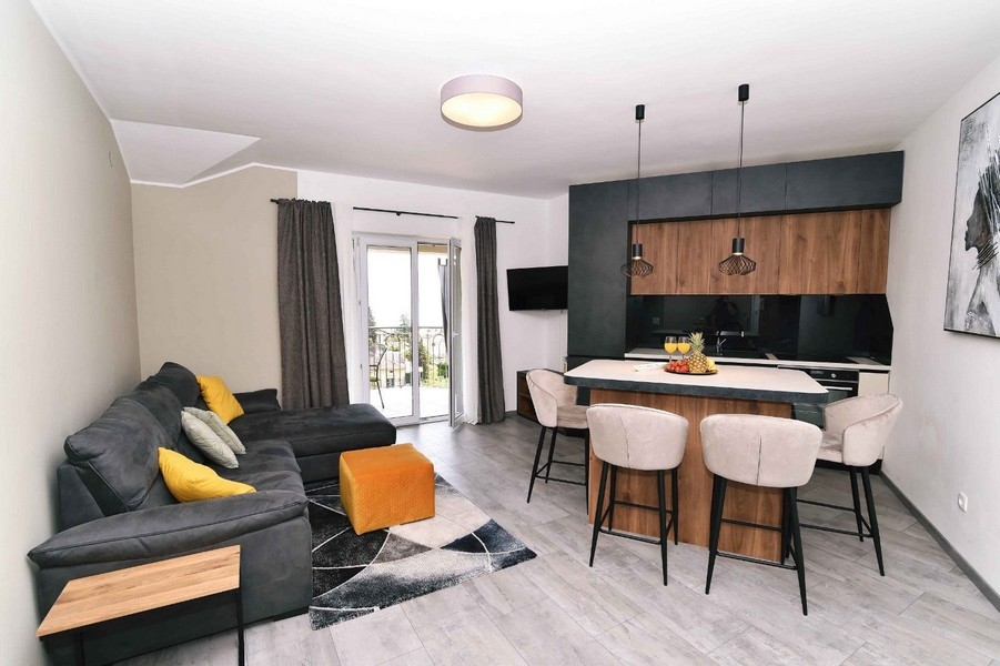 Jasny salon z nowoczesnymi meblami, dostępem do balkonu i widokiem na morze, w centralnej lokalizacji.