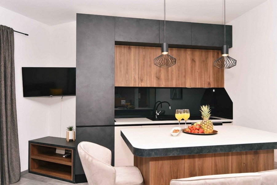 Stylowa kuchnia z drewnianymi frontami, nowoczesnym designem i przestronną powierzchnią roboczą.