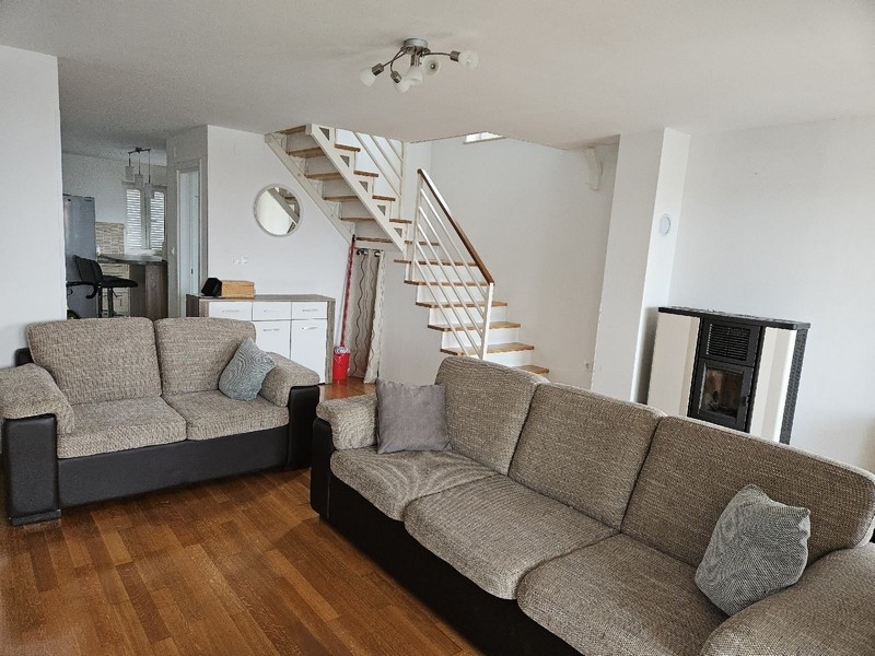 Pokój dzienny z sofą, schodami i piecem na pellet