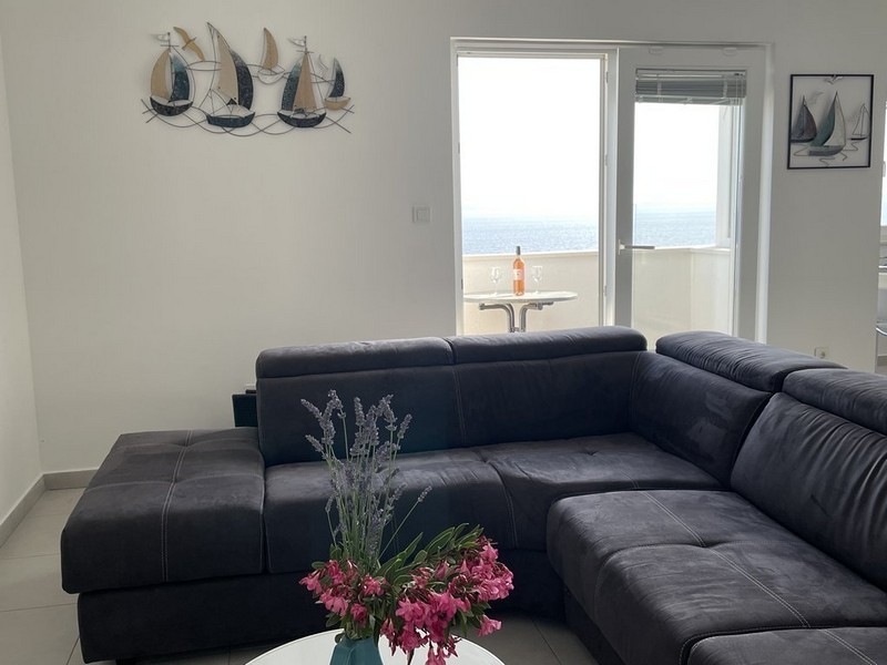 Pokój dzienny z ciemną narożną sofą i widokiem na morze
