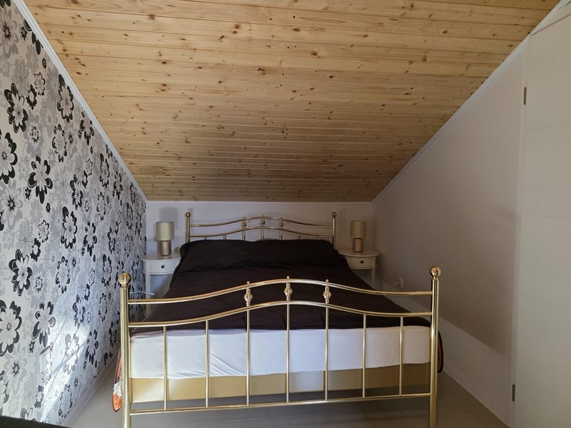 Sypialnia na poddaszu ze skośnym sufitem i podwójnym łóżkiem