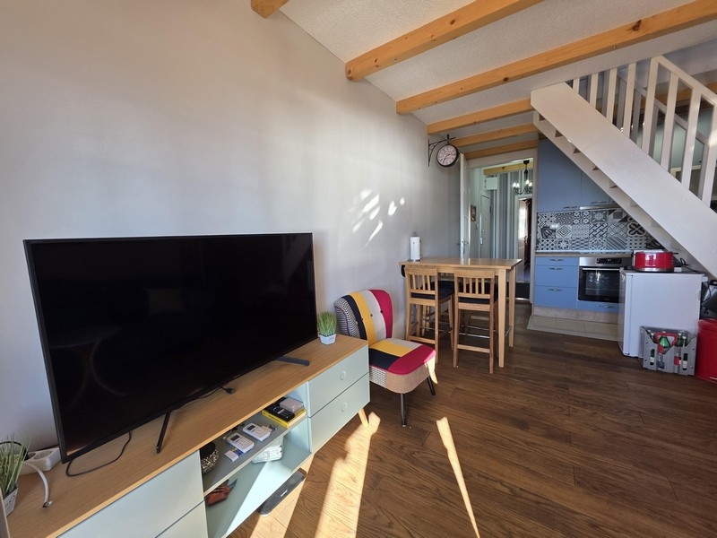 Pokój dzienny z TV, stołem jadalnym i otwartą kuchnią