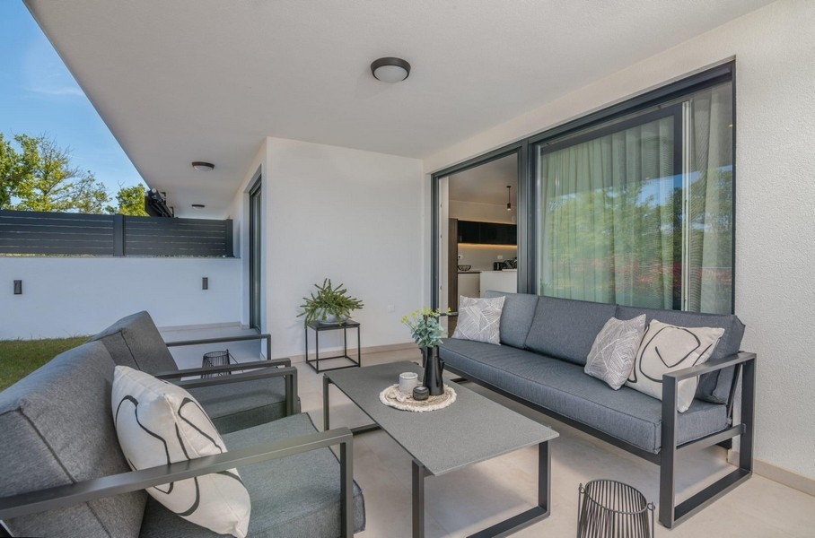 Zadaszony taras z nowoczesnymi miejscami do siedzenia i widokiem na ogród