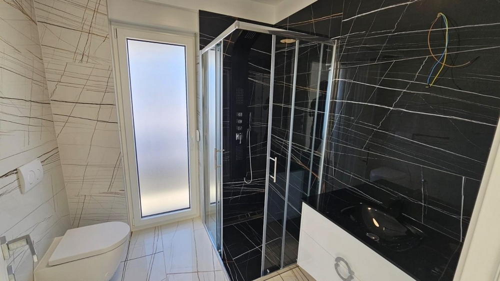 Stylowa łazienka z prysznicem i ciemnymi kafelkami