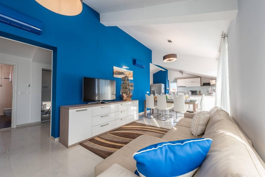 Część dzienna z niebieską ścianą i otwartą kuchnią