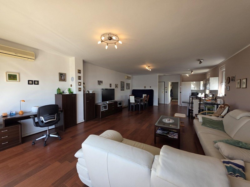 Jasny salon z parkietem, skórzaną sofą i widokiem na morze