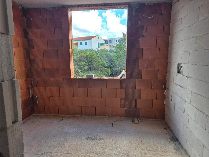 Niewykończona przestrzeń mieszkalna z widokiem na sąsiednie domy przez duże okno