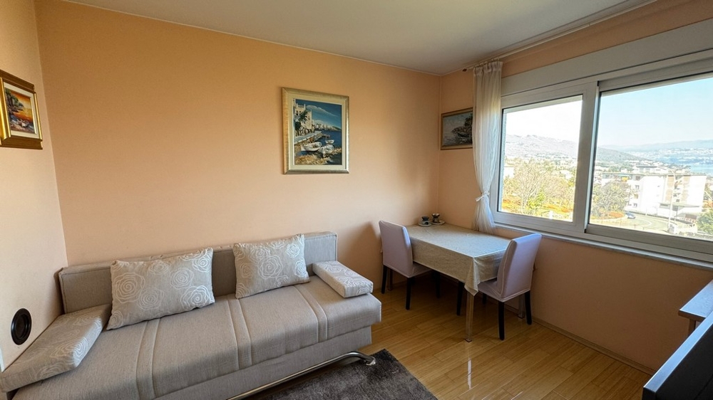 Pokój dzienny z sofą, stołem i dużym oknem z widokiem na morze