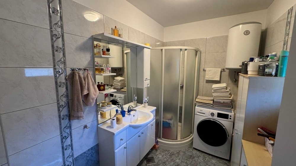 Łazienka z prysznicem, pralką i umywalką z lustrem