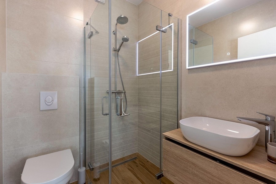 Łazienka ze szklanym prysznicem i drewnianymi detalami