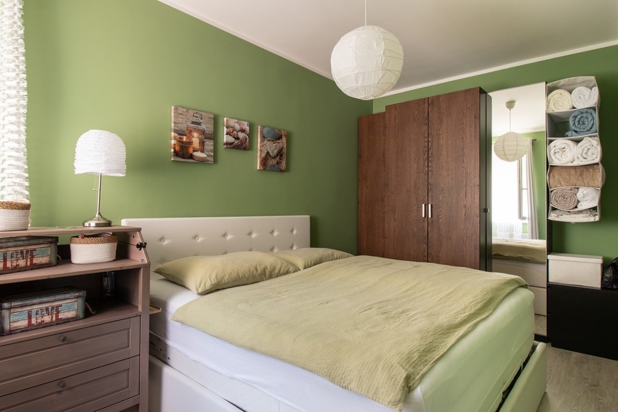 Sypialnia z pomalowaną na zielono ścianą
