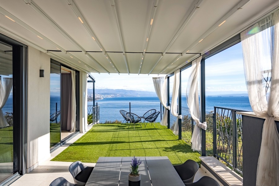Zadaszony taras z ogrodem i panoramicznym widokiem na morze.