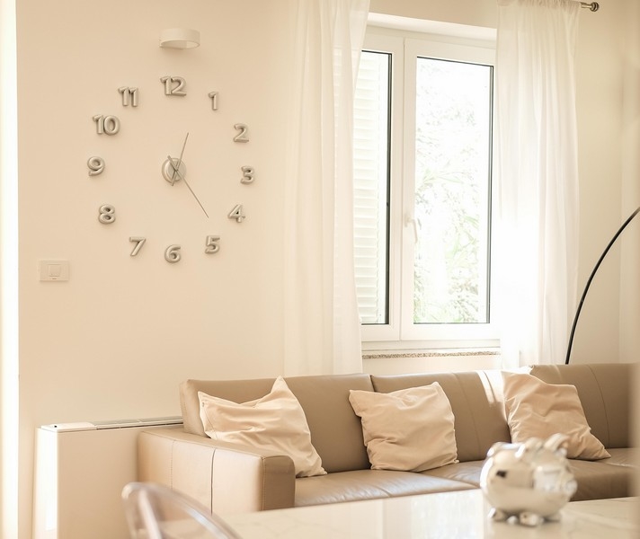 Pokój dzienny z zegarem ściennym i widokiem na zieleń