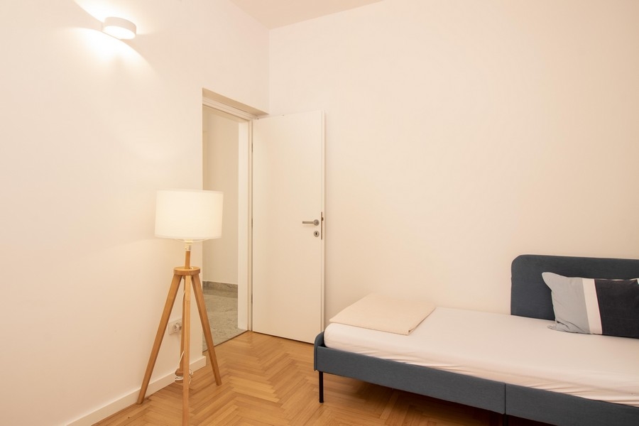 Druga sypialnia z lampą podłogową i drewnianą podłogą