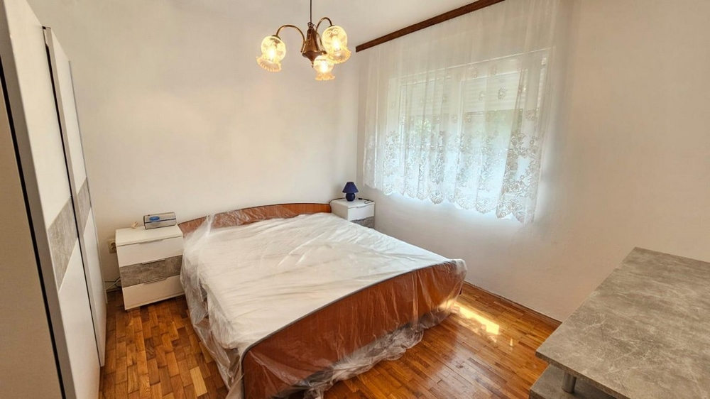 Sypialnia z łóżkiem małżeńskim, szafą i oknem dziennym