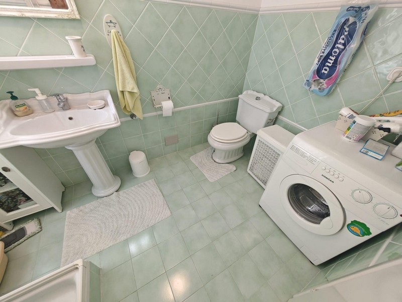 Łazienka z pralką i zielonymi płytkami