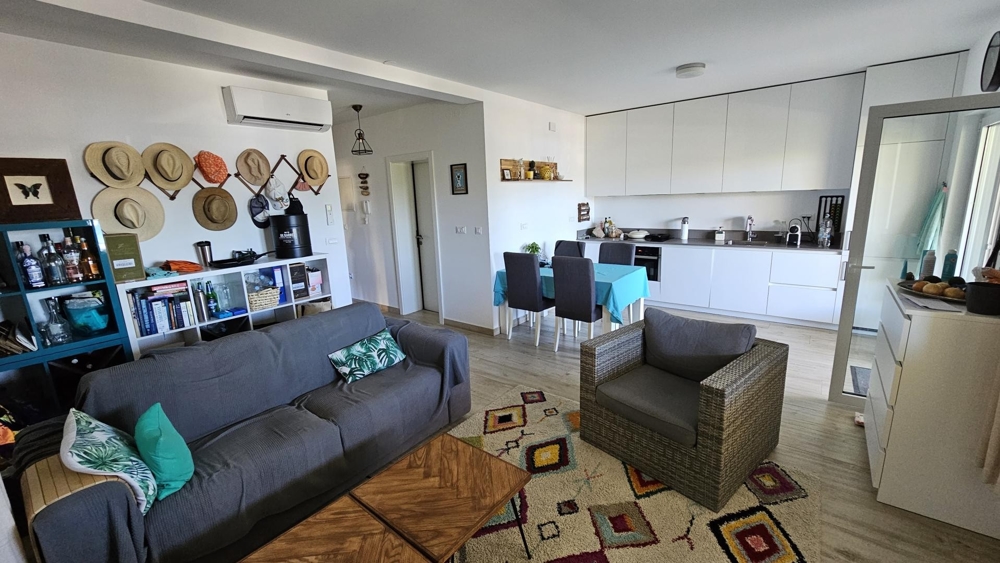 Część dzienna z sofą, fotelem i otwartą kuchnią