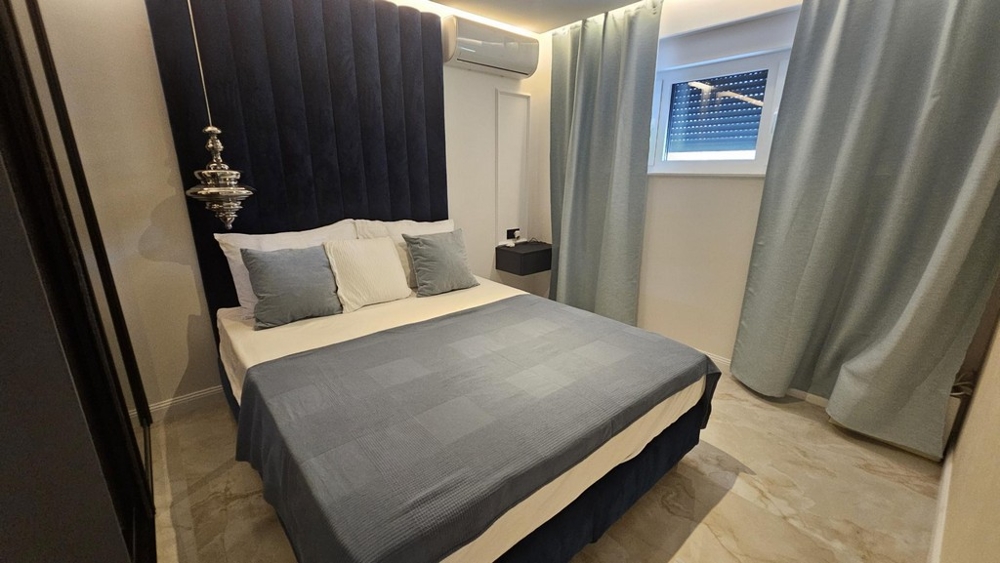 Sypialnia z podwójnym łóżkiem i ciemnoniebieskim zagłówkiem