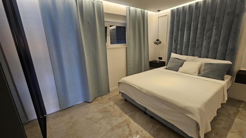 Sypialnia z podwójnym łóżkiem i jasnoniebieskim zagłówkiem