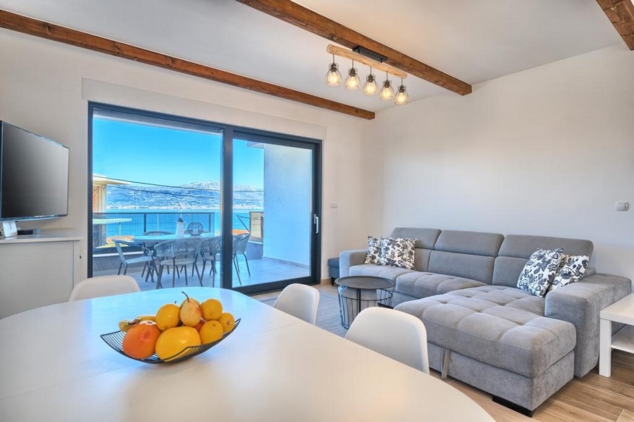 Pokój dzienny z sofą i wyjściem na taras z widokiem na morze