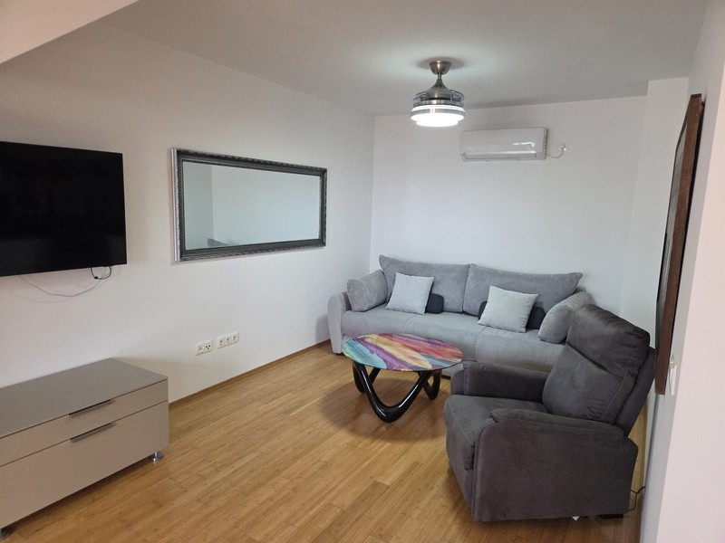 Pokój dzienny z szarą kanapą, fotelem i lustrem ściennym