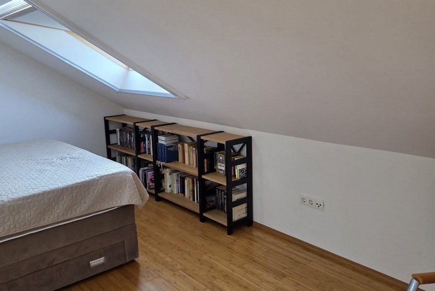 Sypialnia ze skośnym sufitem i półkami na książki