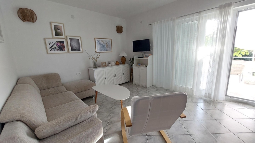 Jasny salon z sofą, fotelem i wyjściem na taras