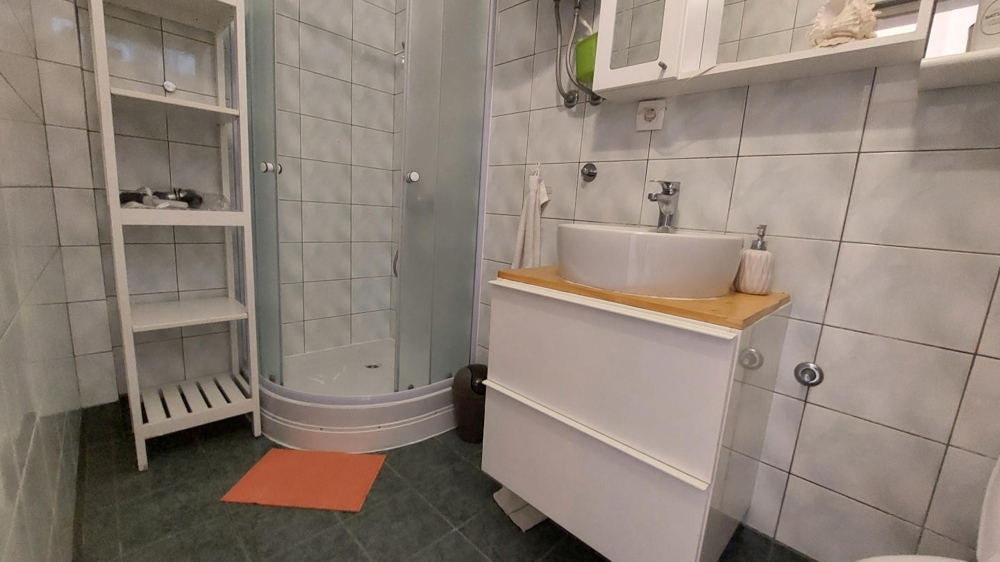 Łazienka z prysznicem, umywalką i płytkami