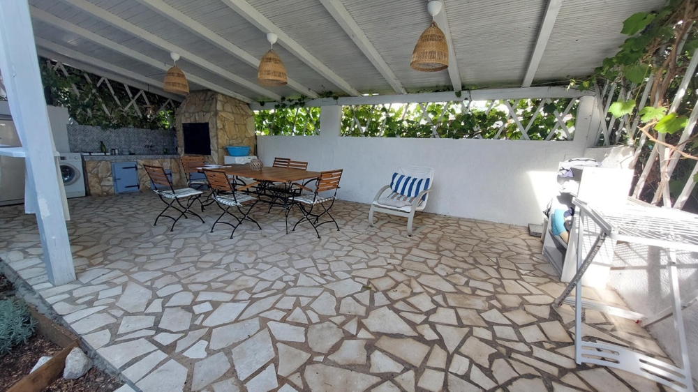 Zadaszona kuchnia letnia ze stołem jadalnym i miejscem do grillowania