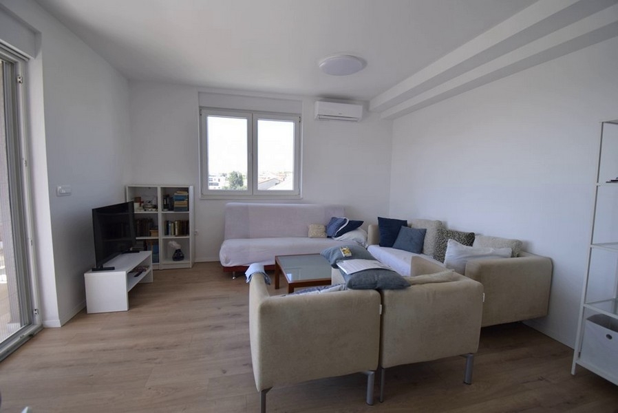 Pokój dzienny z częścią wypoczynkową, telewizorem i oknem od frontu