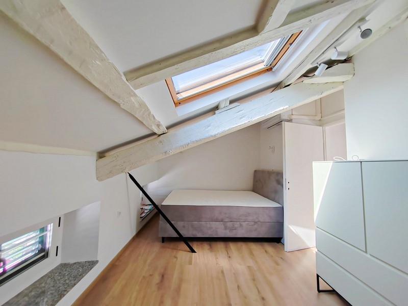 Druga sypialnia na poddaszu z łóżkiem i belkami dachowymi