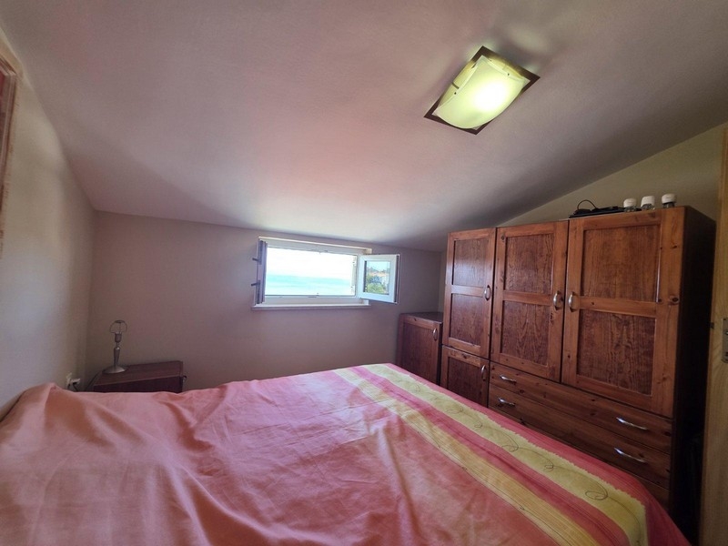 Sypialnia z podwójnym łóżkiem i oknem z widokiem na morze.