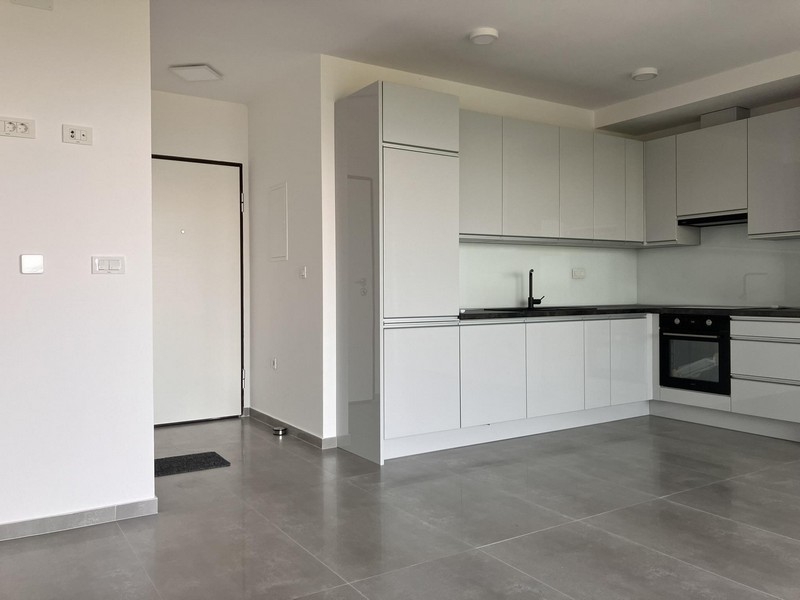 Otwarta kuchnia z białą wyposażoną kuchnią i podłogą wyłożoną kafelkami